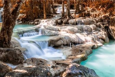 Cascada si apa albastra de smarald in padurea de toamna